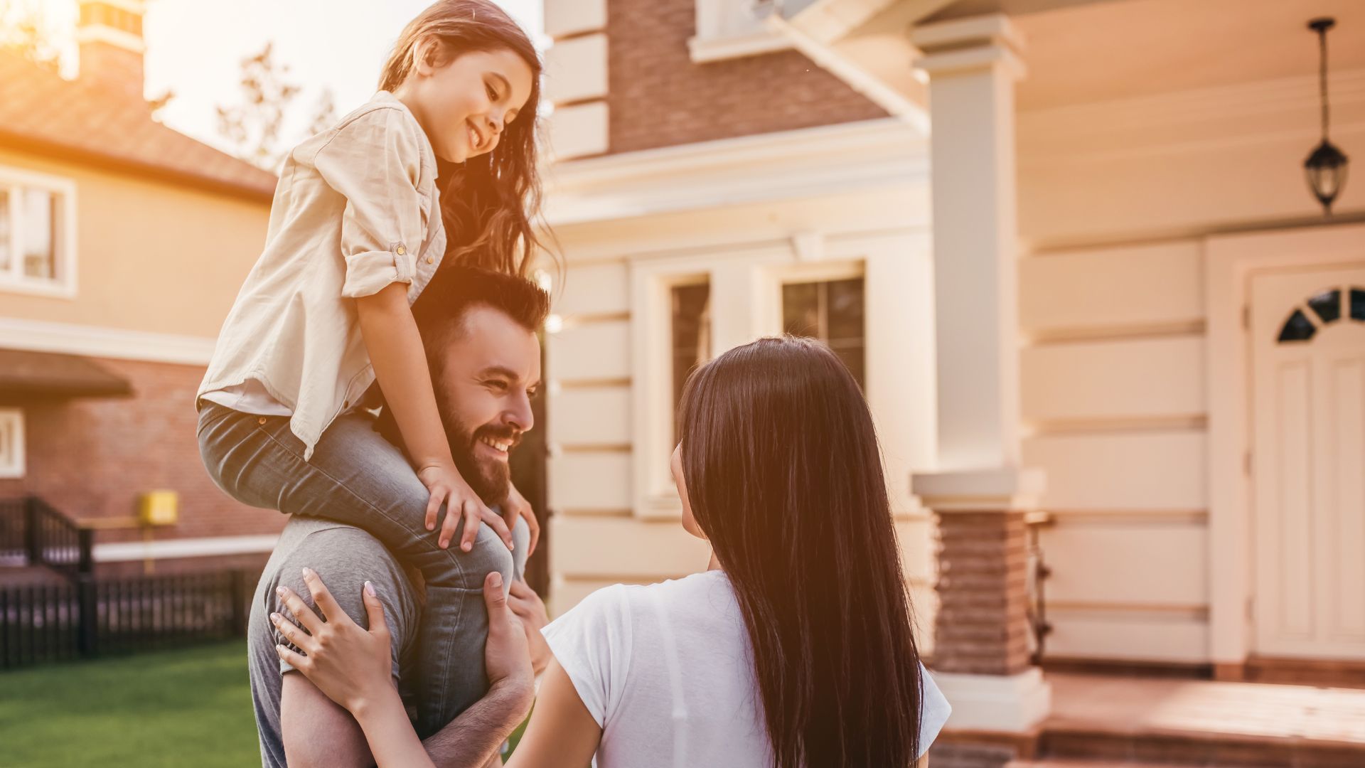 A family stands on a lush lawn, admiring their beautiful, freshly painted house