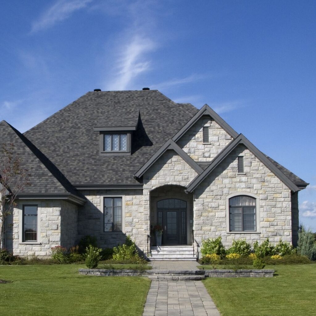 Stone house with a dark grey asphalt shingle roof