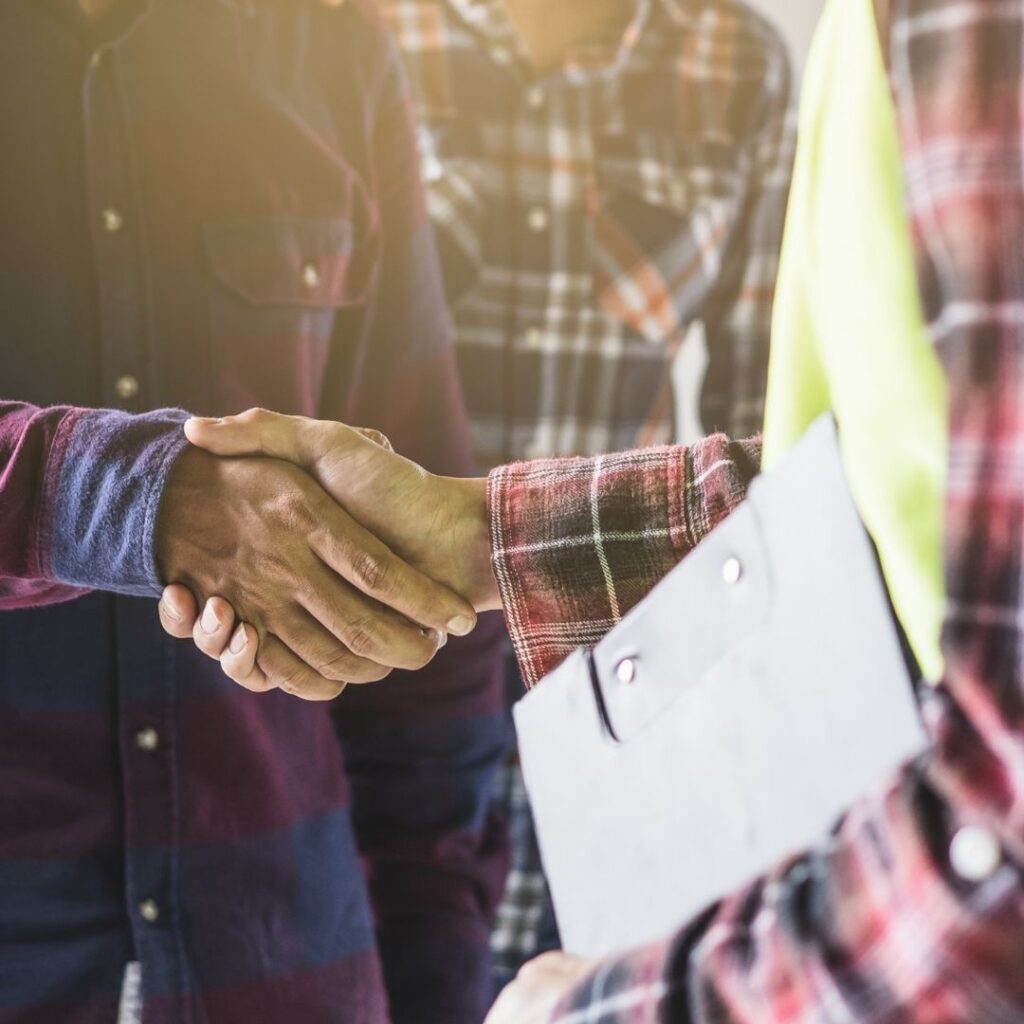Homeowner shaking hands with contractor holding clipboard